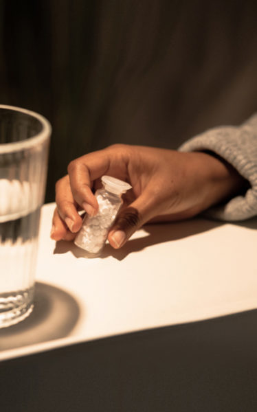 Eine Frau hält Schüßler Salze in einer kleinen Glasflasche in ihrer Hand
