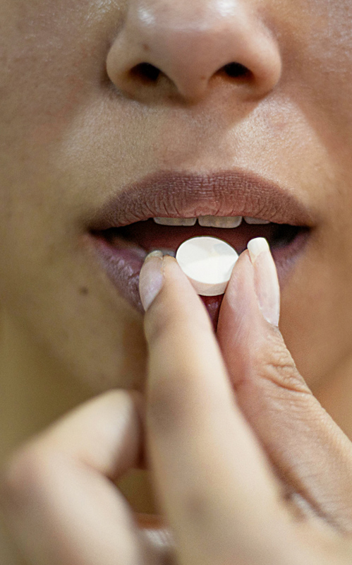 Eine Frau steckt sich eine Schüßler-Salz-Tablette in den Mund